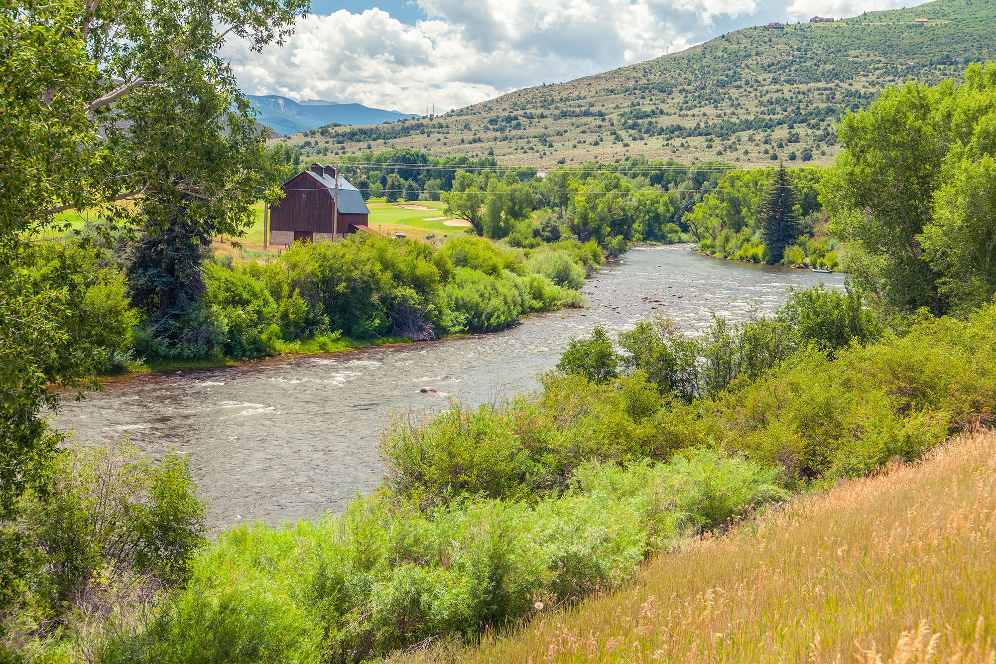River flowing through a lush green landscape with mountains in the background