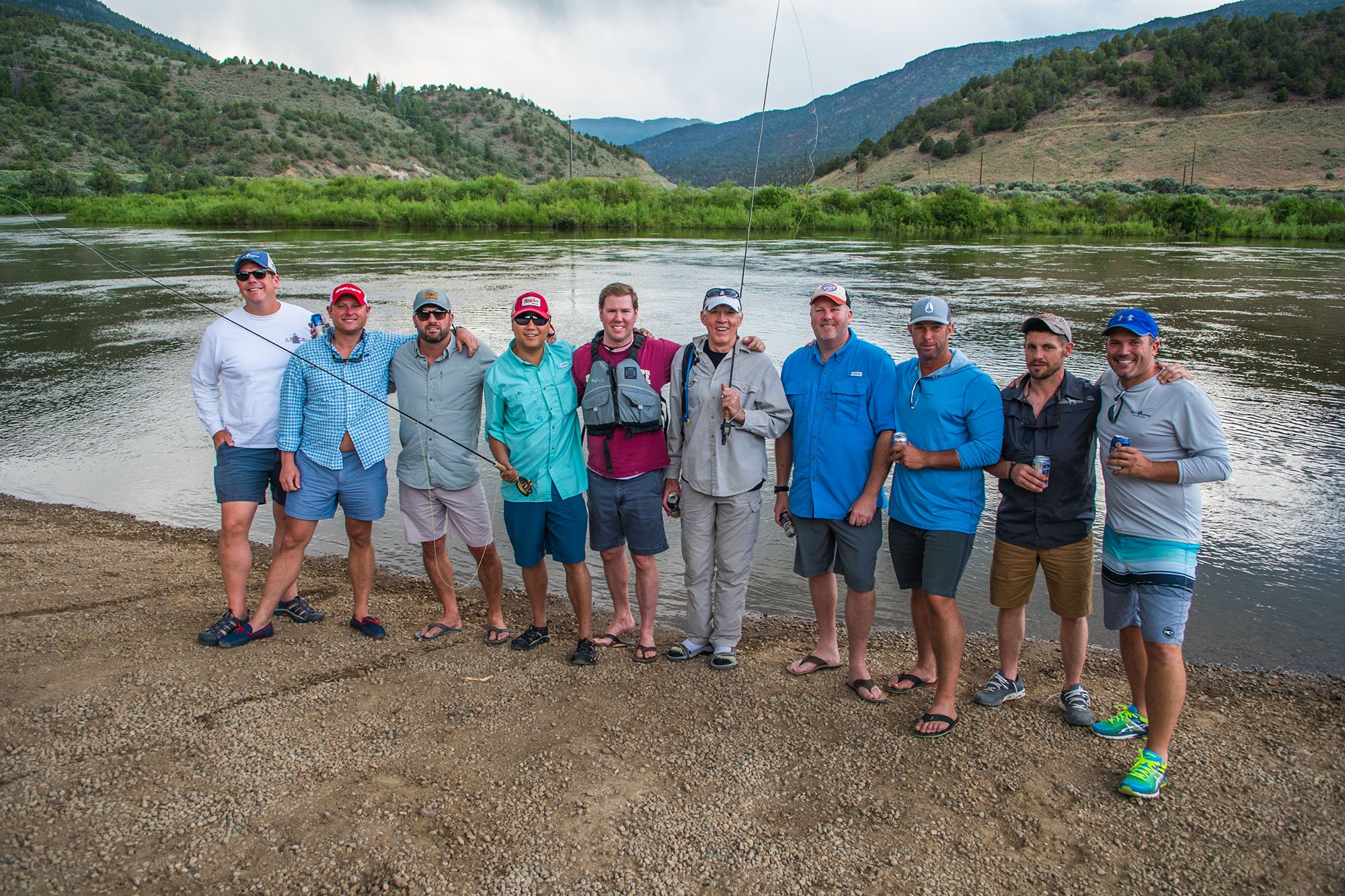 Group of people posing for a photo by a river with mountains in the background