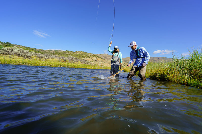 An angler landing a fish on a river with the help of one of the Vail Valley Anglers guides.