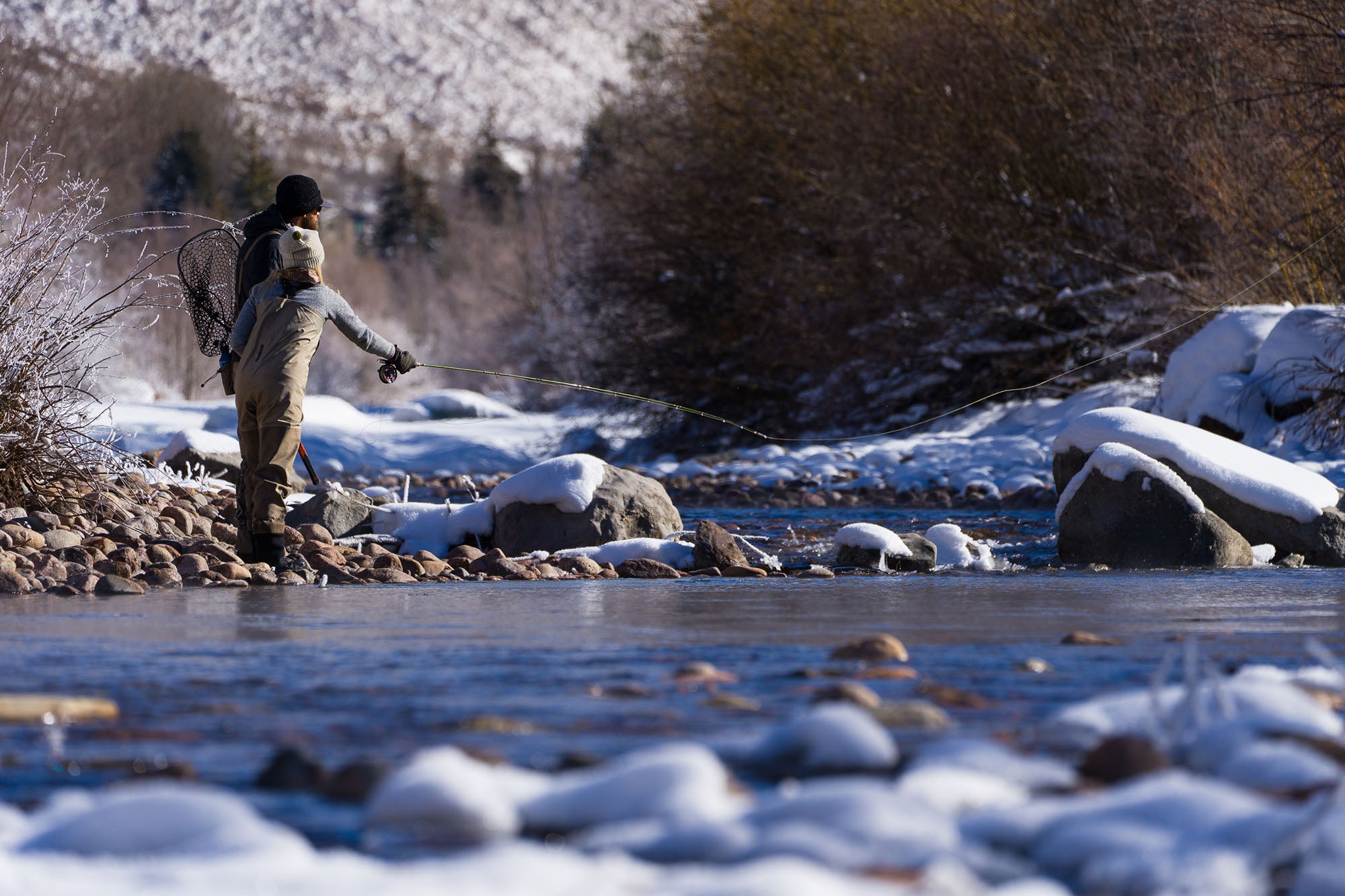 Two anglers fishing in a snowy river landscape on a guided trip with Vail Valley Anglers