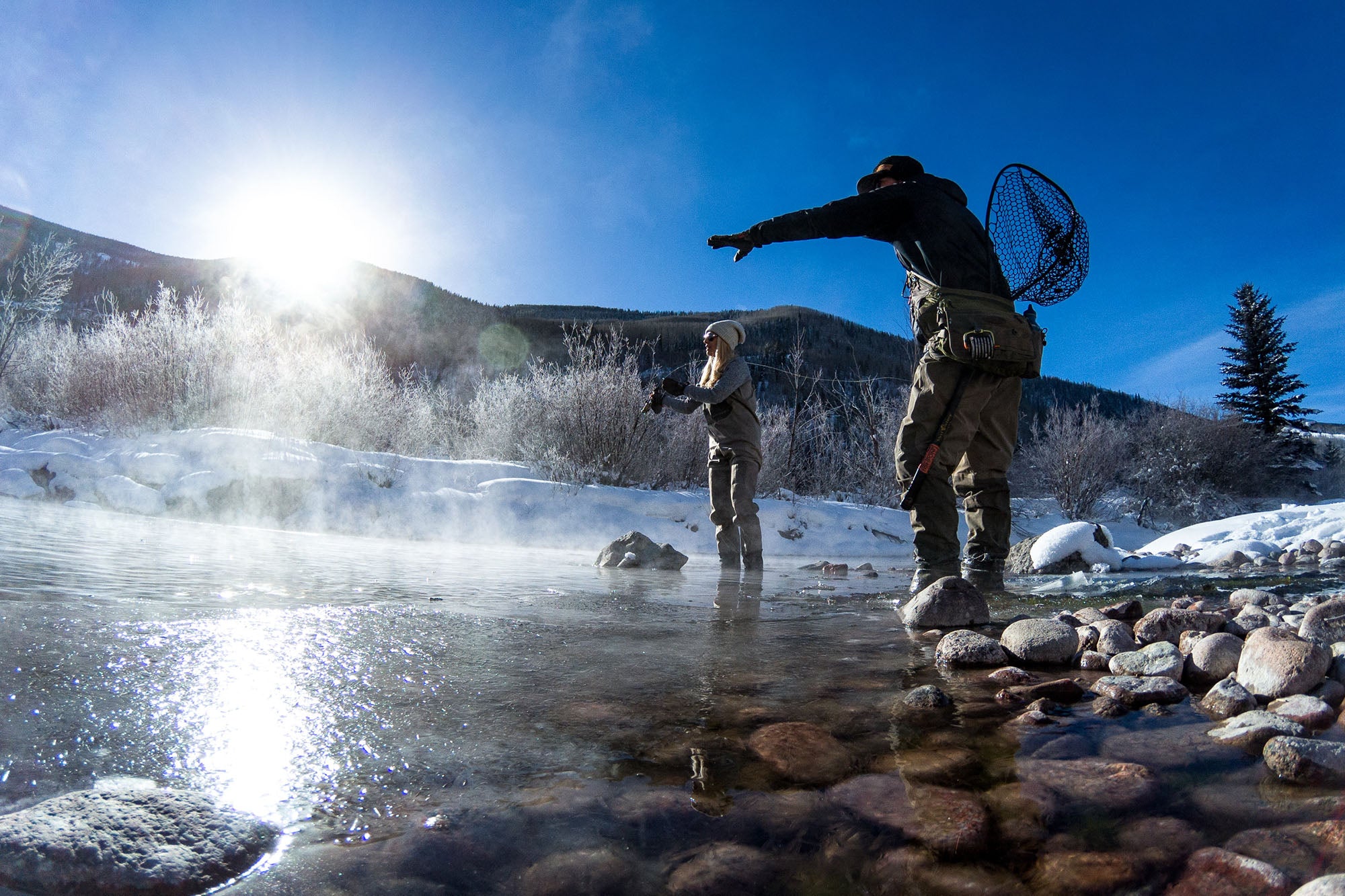 Two people fishing an early winter Morning on the Eagle River with mountains in the background